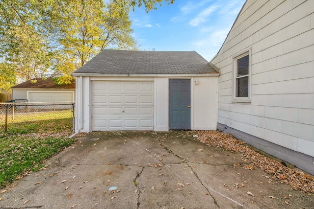 garage featuring fence and concrete driveway
