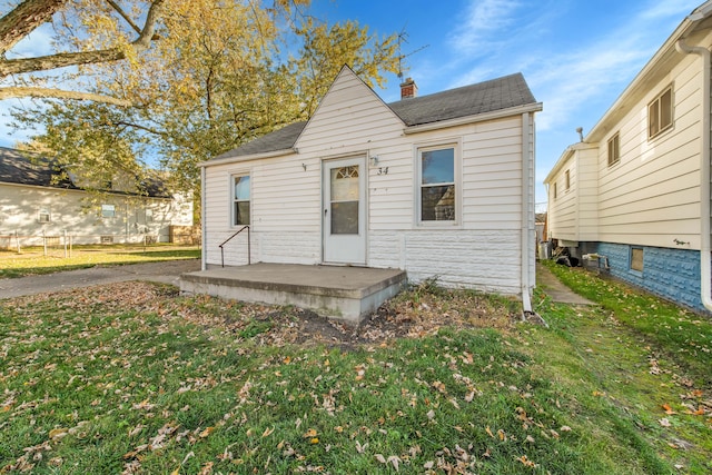 rear view of house featuring roof with shingles and a yard