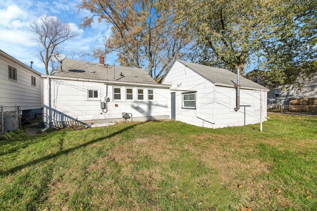 back of house featuring fence and a lawn