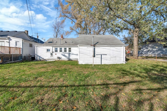 rear view of house featuring a yard and fence