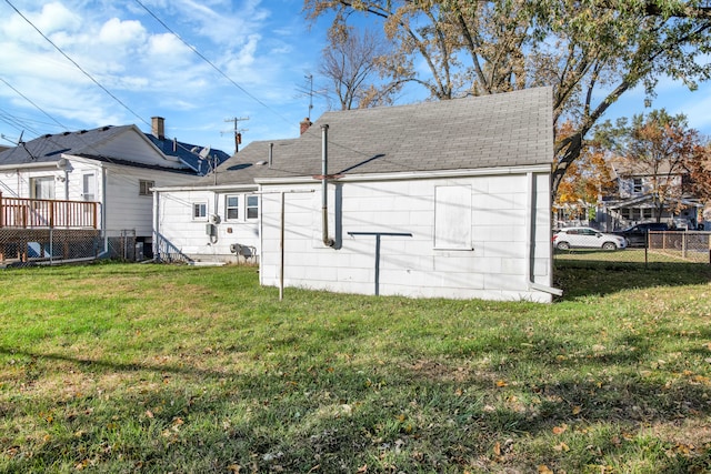 back of property featuring a lawn, fence, a deck, and a shingled roof