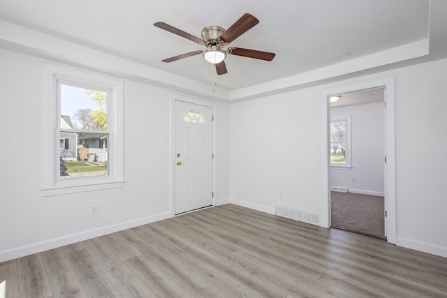 foyer entrance with baseboards, a ceiling fan, wood finished floors, and visible vents