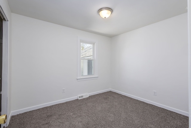 unfurnished room featuring baseboards, visible vents, and dark carpet