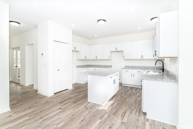 20233 Sunset Ave, Livonia, MI 48152 - kitchen with a sink, a center island, light wood-type flooring, and light stone countertops