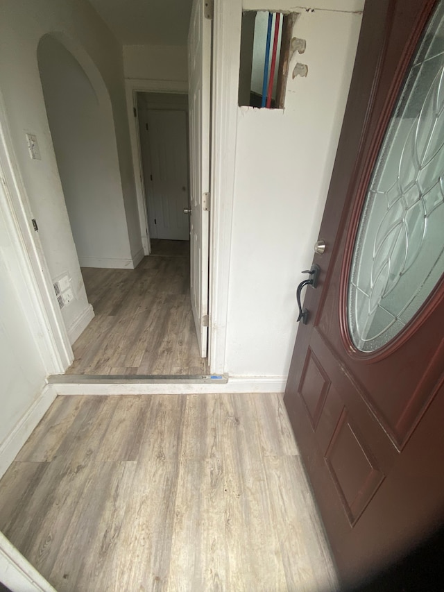 entryway featuring baseboards, arched walkways, and wood finished floors