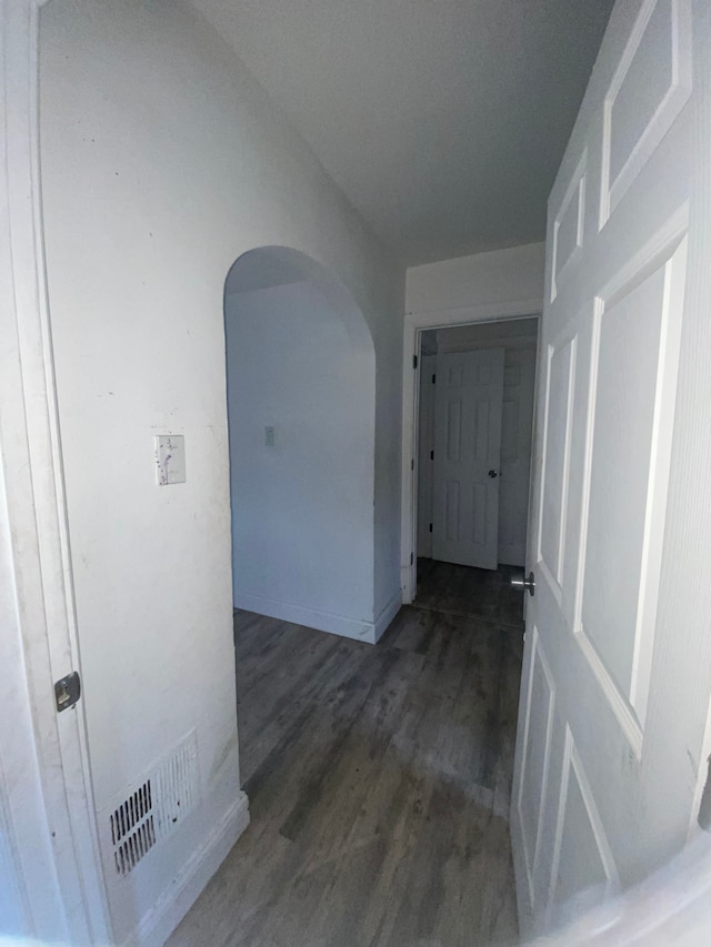hallway featuring visible vents, arched walkways, and wood finished floors