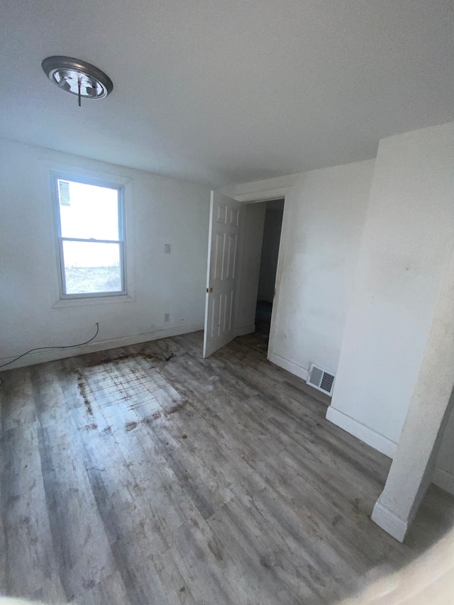 unfurnished room with wood finished floors, baseboards, and visible vents