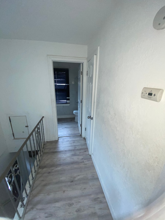 hall with baseboards and wood finished floors