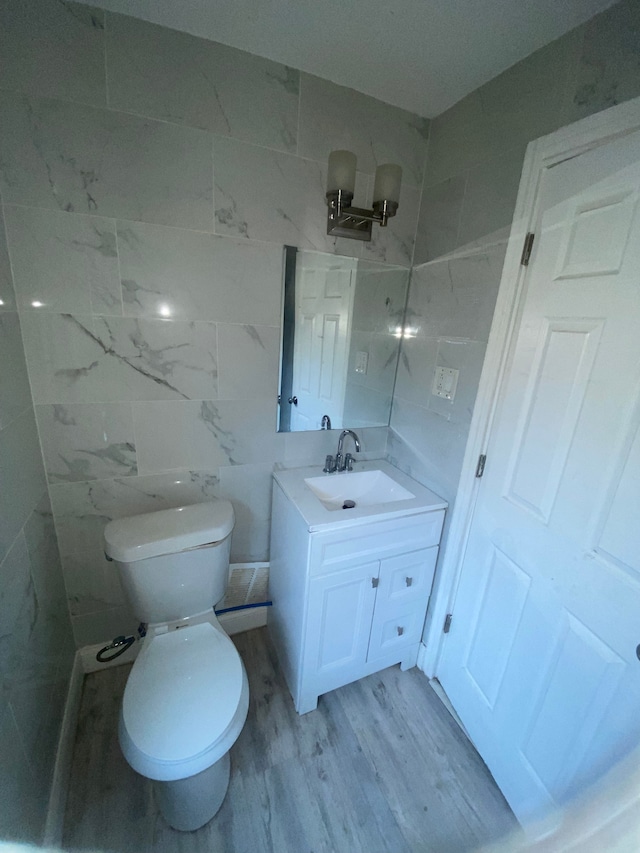 bathroom featuring vanity, tile walls, toilet, and wood finished floors
