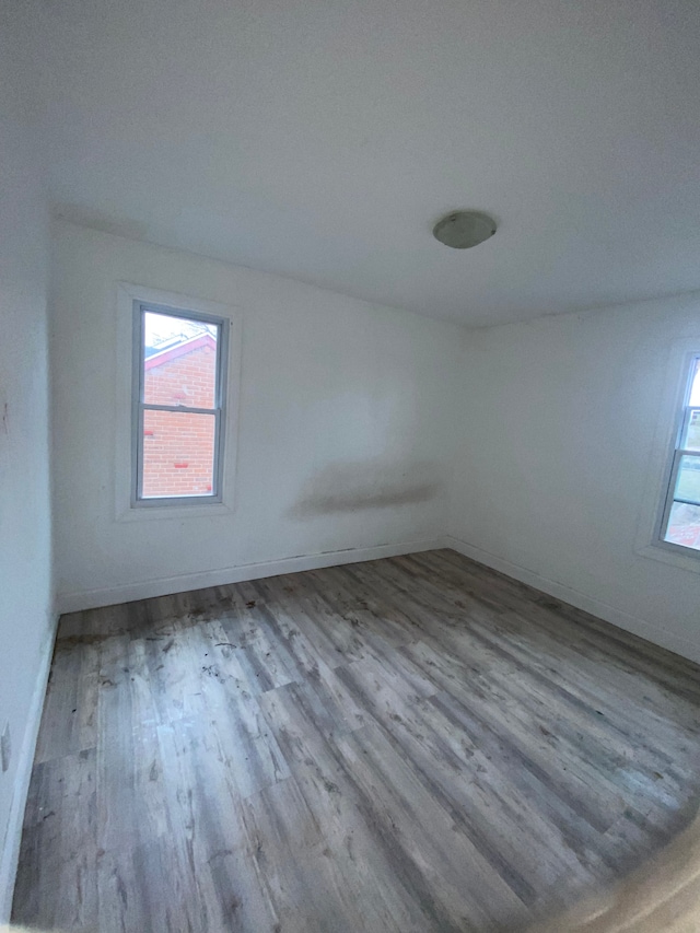 unfurnished room with a healthy amount of sunlight, wood finished floors, and baseboards