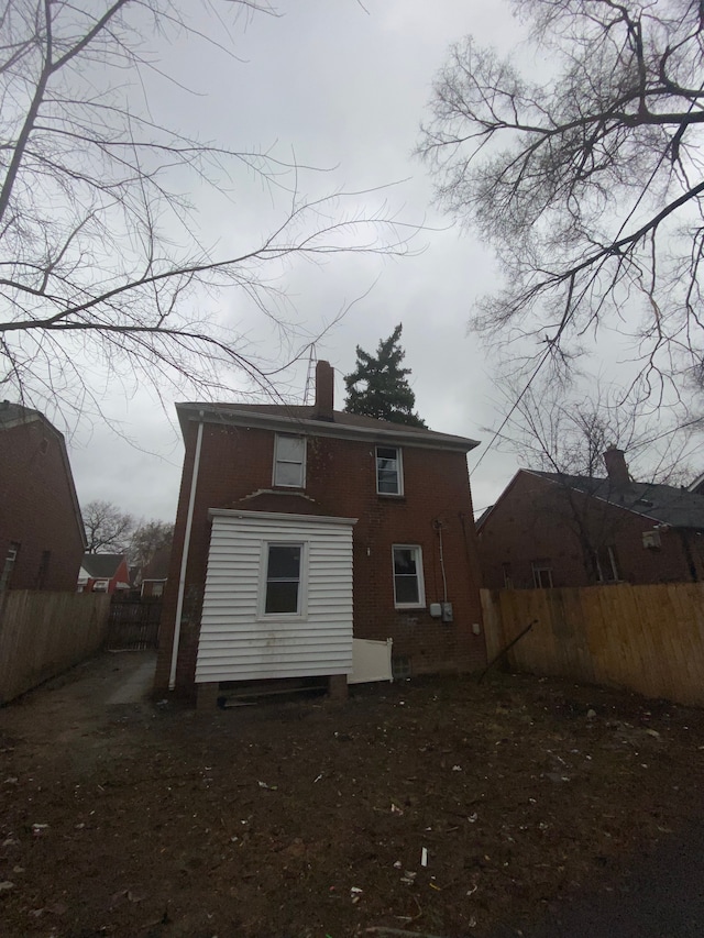 back of property with a chimney and fence