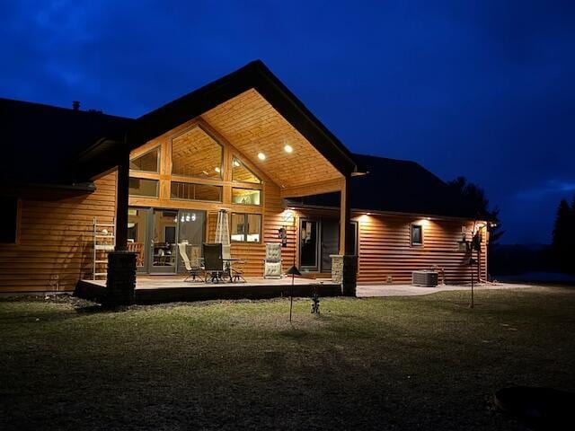 back of house at twilight featuring cooling unit, a yard, and a patio area