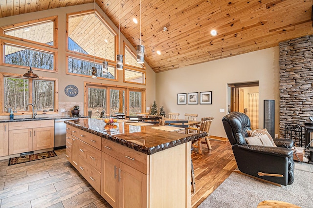 kitchen with dark stone counters, stainless steel dishwasher, wood ceiling, a sink, and open floor plan