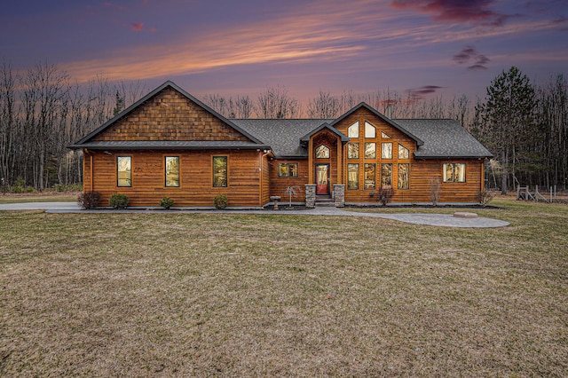 rustic home with roof with shingles and a yard