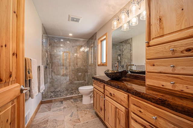 full bath with toilet, vanity, a shower stall, and visible vents