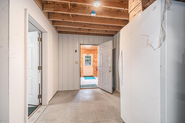 corridor with wooden walls and unfinished concrete flooring