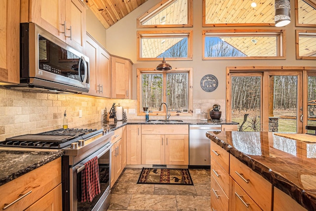 kitchen with dark stone countertops, a sink, wood ceiling, stainless steel appliances, and decorative backsplash