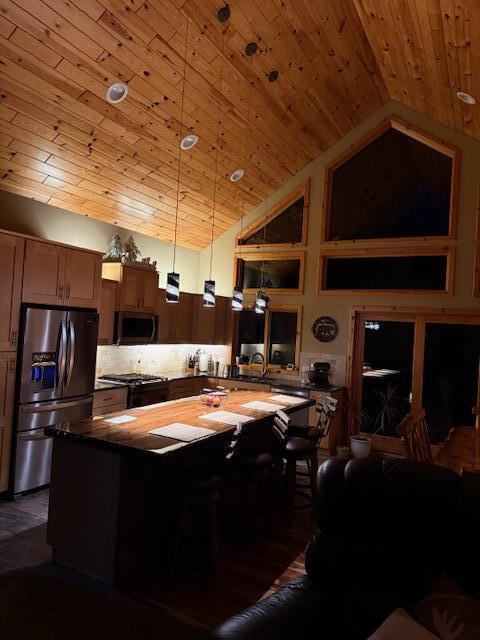 kitchen with wooden ceiling, decorative light fixtures, stainless steel appliances, backsplash, and high vaulted ceiling