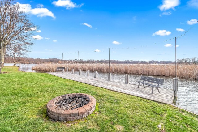 view of yard with a water view, a fire pit, and a boat dock