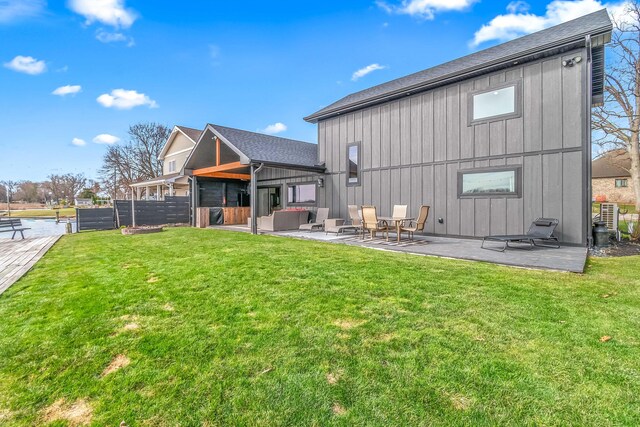 rear view of property featuring a yard, a patio, and board and batten siding