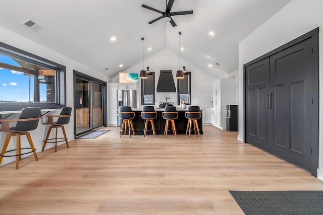 kitchen featuring a breakfast bar, vaulted ceiling, visible vents, ceiling fan, and light wood finished floors