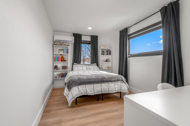 bedroom with a wall mounted air conditioner, recessed lighting, light wood-style floors, and baseboards