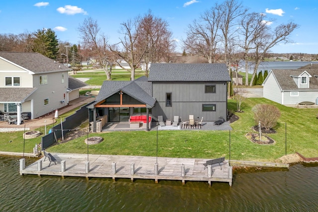back of house with a patio, a residential view, a lawn, a water view, and a shingled roof