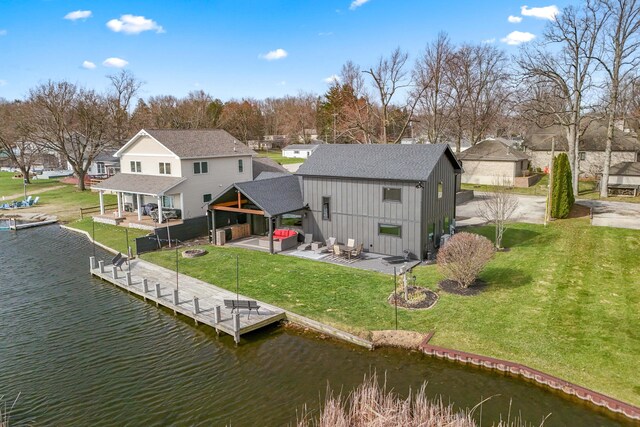 back of property with a water view, a patio area, and a lawn
