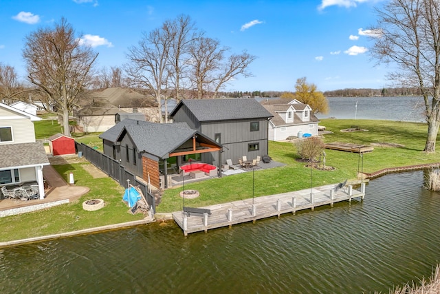 rear view of house featuring a patio, a yard, a fire pit, and a water view