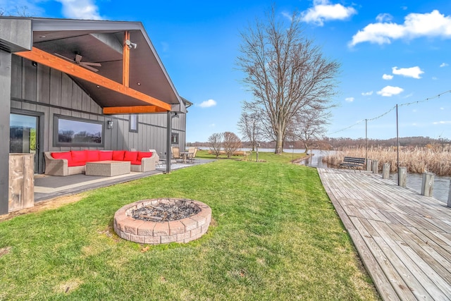 view of yard with an outdoor living space with a fire pit, a patio area, and a water view