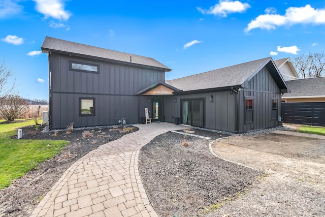 rear view of property featuring a yard, a patio, board and batten siding, and a shingled roof
