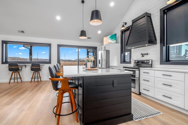 kitchen with a breakfast bar, premium range hood, light countertops, visible vents, and appliances with stainless steel finishes