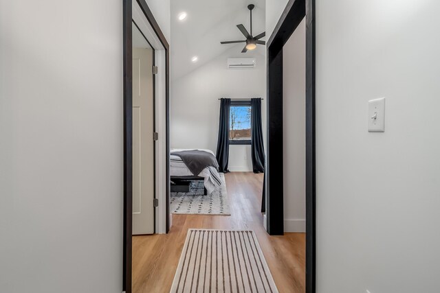 corridor featuring a wall mounted AC, baseboards, vaulted ceiling, recessed lighting, and light wood finished floors