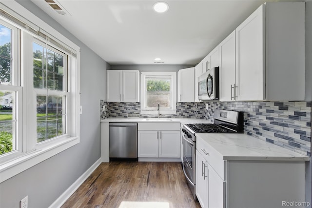 13446 Fisk Ave, Warren, MI 48089 - kitchen with stainless steel appliances, dark wood-style floors, decorative backsplash, light stone counters, and white cabinetry