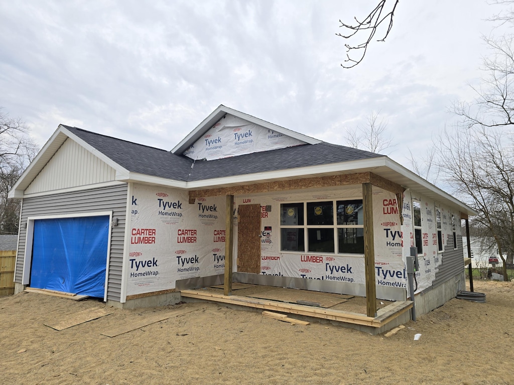 property under construction featuring an attached garage and a shingled roof