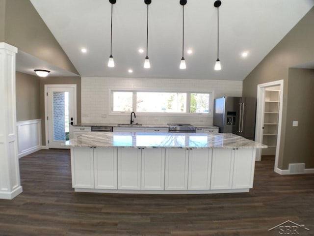 kitchen featuring lofted ceiling, a large island, white cabinets, and stainless steel fridge