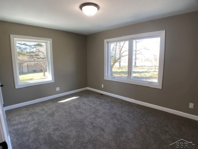 unfurnished room featuring dark colored carpet and baseboards
