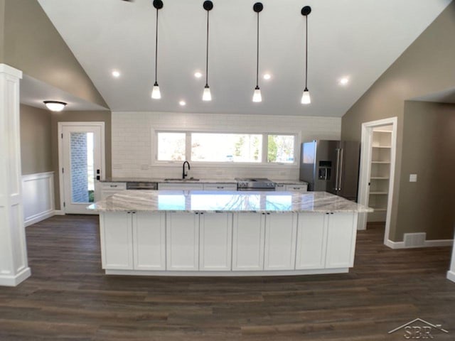 kitchen with a spacious island, white cabinets, vaulted ceiling, and stainless steel appliances