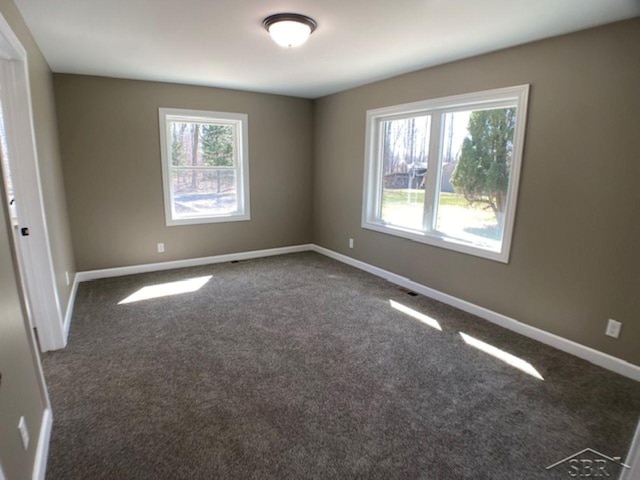 carpeted spare room with plenty of natural light and baseboards