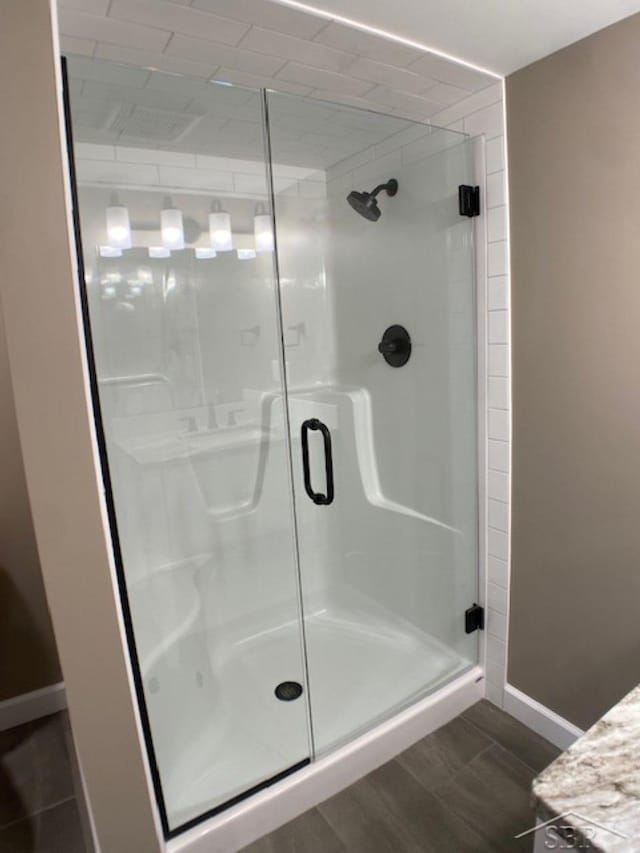 full bath with wood finished floors, a stall shower, and baseboards