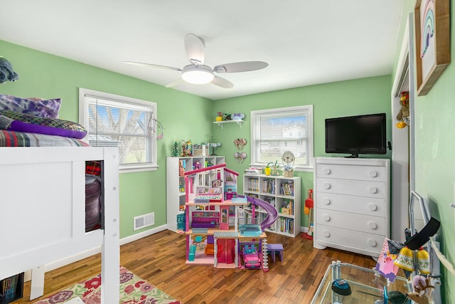 bedroom featuring wood finished floors, baseboards, multiple windows, and visible vents