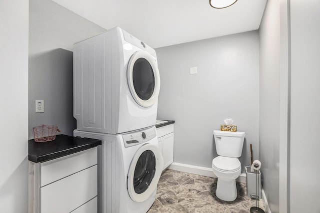 laundry area with laundry area, stacked washer / drying machine, and baseboards
