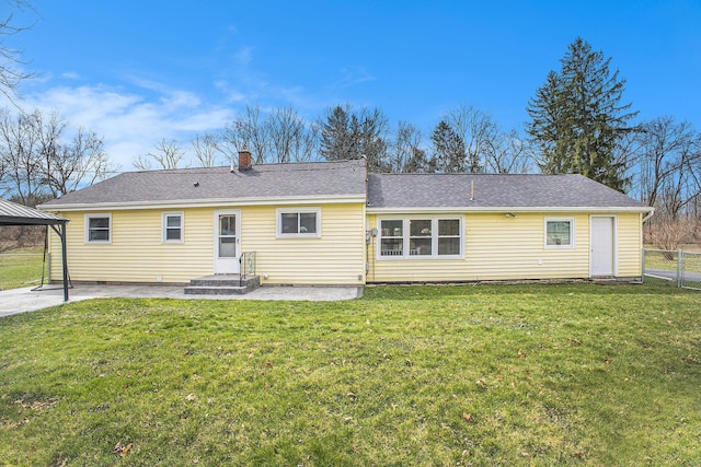 rear view of house featuring a yard, a patio, roof with shingles, fence, and a chimney