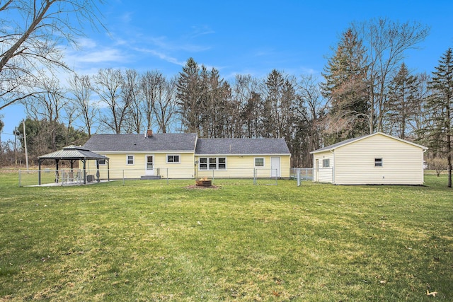 back of property with an outdoor fire pit, a gazebo, and a lawn