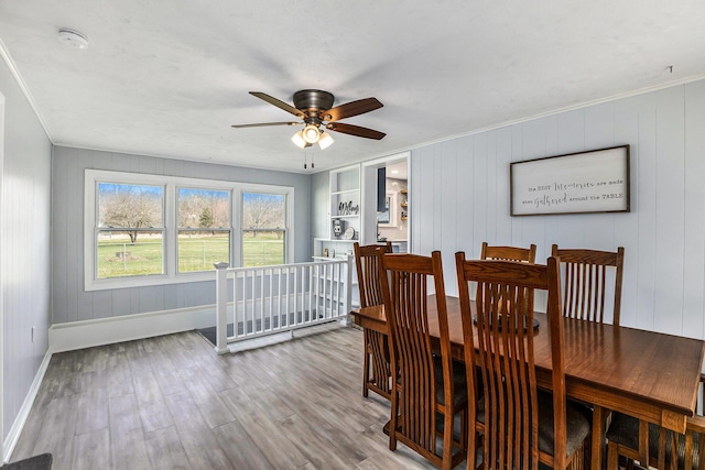 dining room featuring crown molding, wood finished floors, ceiling fan, and baseboards