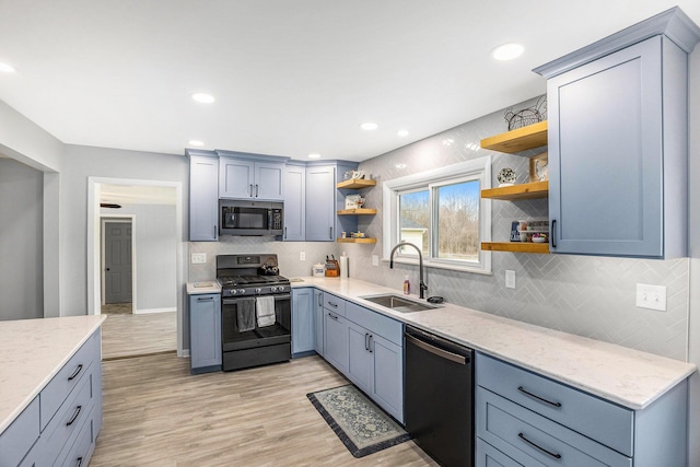 kitchen featuring stainless steel microwave, black gas stove, open shelves, dishwashing machine, and a sink