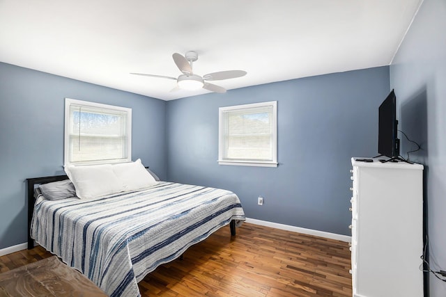 bedroom featuring multiple windows, baseboards, a ceiling fan, and wood finished floors