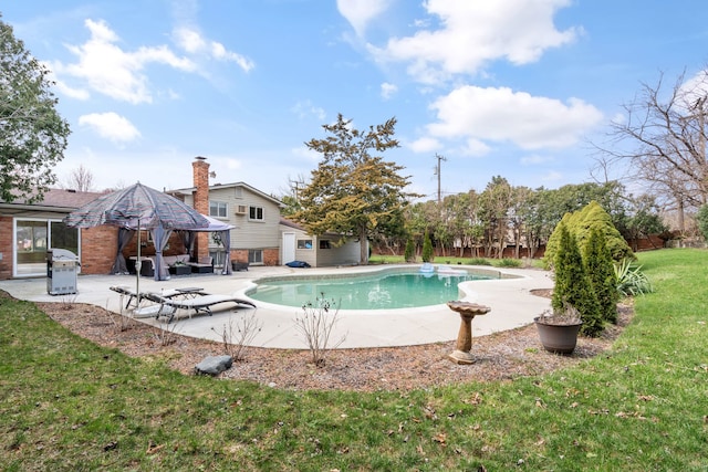 outdoor pool with a lawn, a patio, an outbuilding, and area for grilling