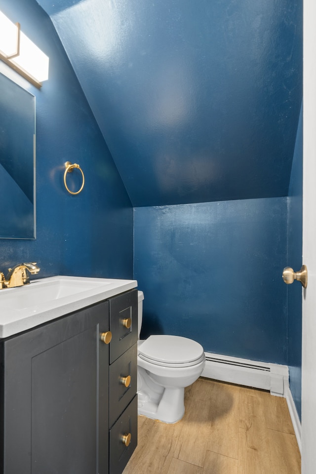bathroom with wood finished floors, lofted ceiling, a baseboard heating unit, and toilet