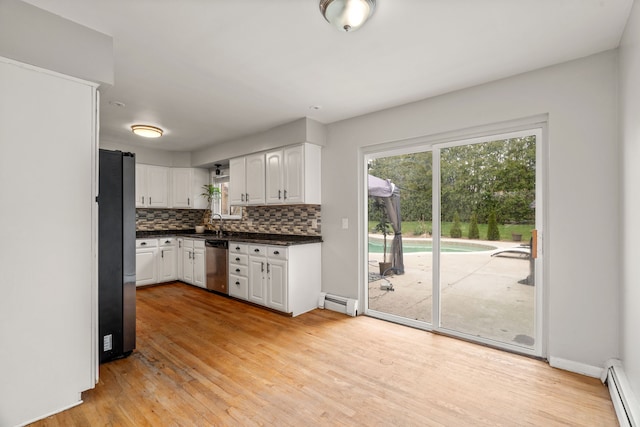 kitchen featuring decorative backsplash, appliances with stainless steel finishes, a baseboard heating unit, light wood finished floors, and white cabinetry